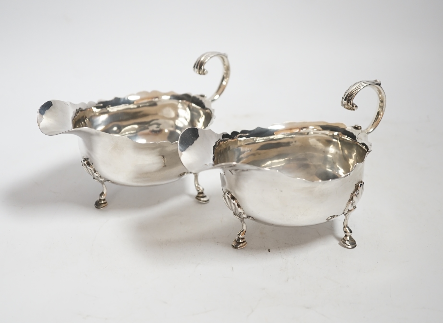 A pair of Edwardian silver sauce boats, with flying scroll handles, Nathan & Hayes, Chester, 1902, length 15.3cm, 9oz.